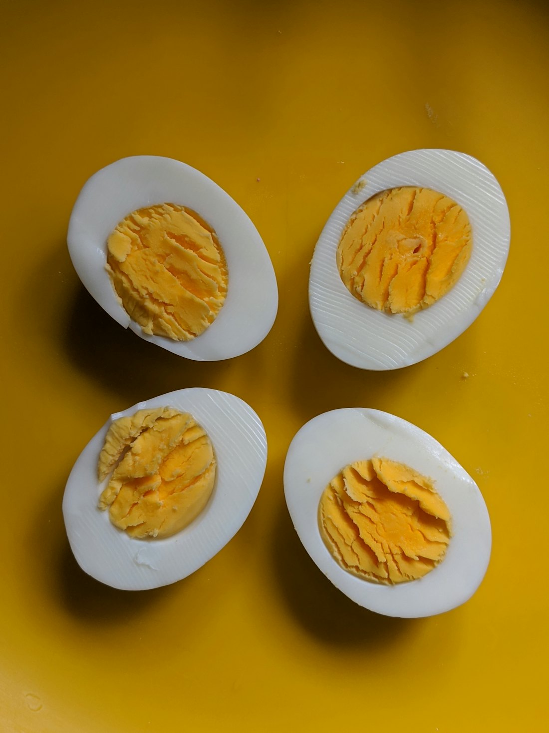 Hard boiled eggs cut in half showing even golden yolks